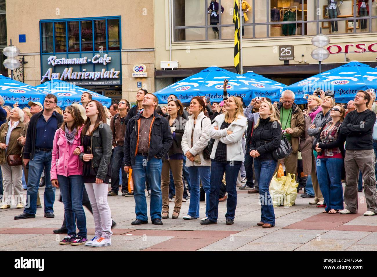Una folla si guarda al Glockenspiel di Marienplatz, Monaco, Germania. Foto Stock