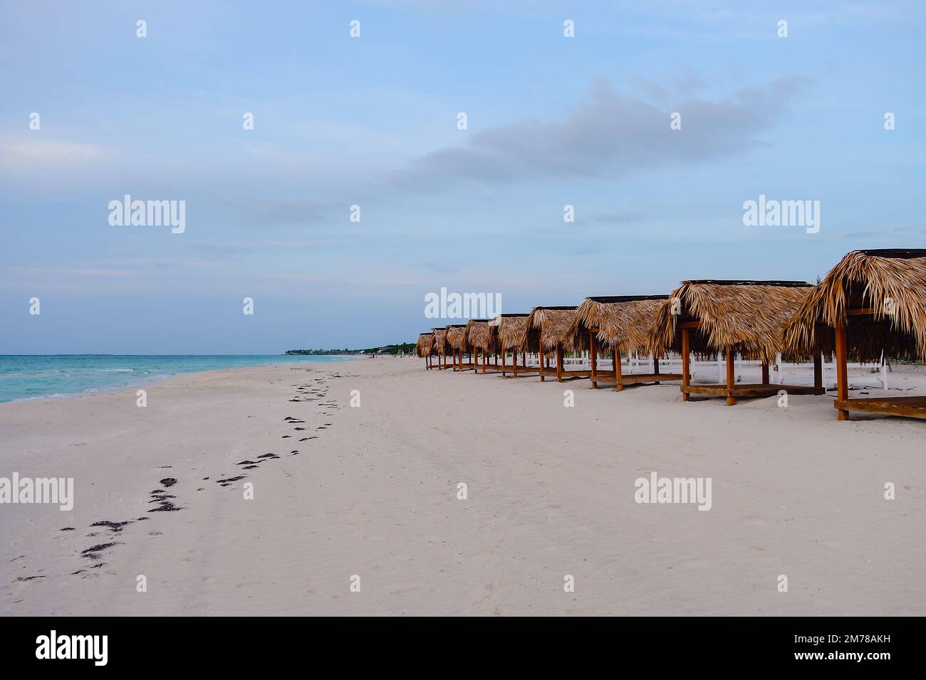 Sedie a sdraio e ombrelloni prima del tramonto su una spiaggia vuota. Foto Stock