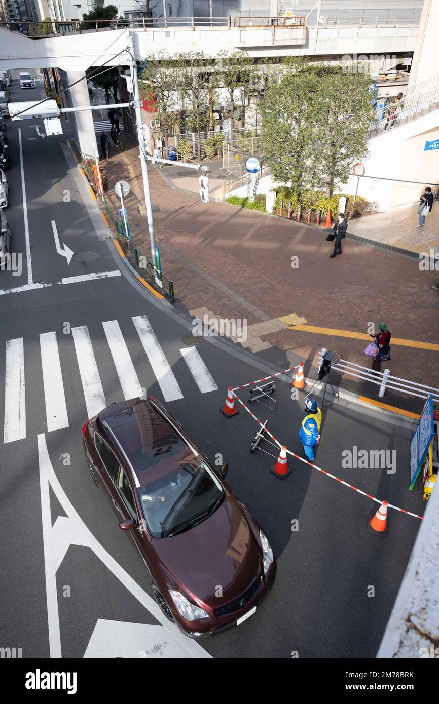 Tokyo, Giappone. 6th Jan, 2023. Un flagger ondeggia attraverso il traffico dei veicoli oltre i lavori stradali all'esterno di una stazione ferroviaria della linea Marunouchi alla stazione della metropolitana M Korakuen, che include un centro commerciale nella stazione in cui i treni entrano. (Credit Image: © Taidgh Barron/ZUMA Press Wire) Foto Stock