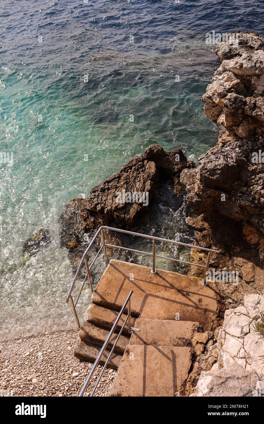 Verticale sopra Vista della spiaggia croata con scale. Bella Pola natura con mare Adriatico e rocce in Istria durante l'estate. Foto Stock