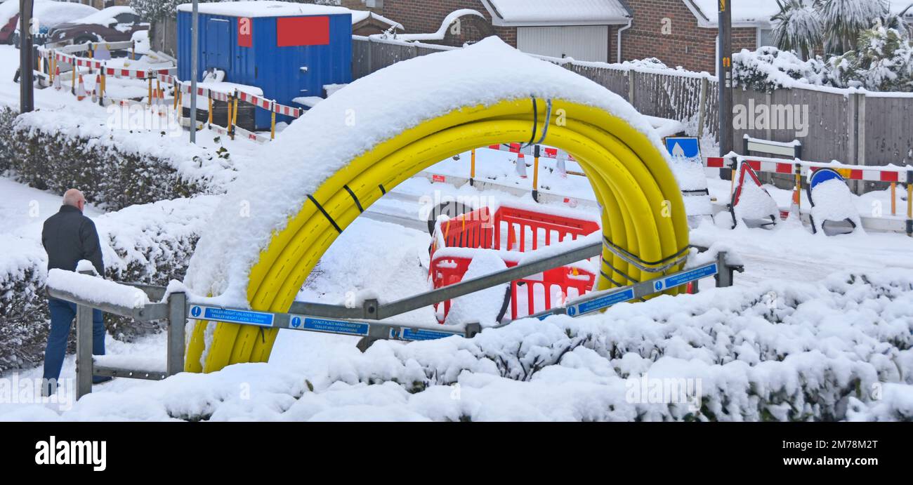 Inverno neve ritarda appaltatori strada lavori in strada villaggio residenziale per sostituire la vecchia rete di acciaio gas inserire nuovo tubo giallo collegato alle case Regno Unito Foto Stock