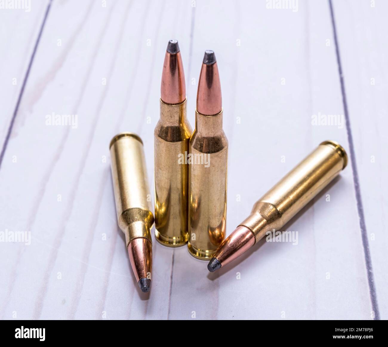 Quattro proiettili utilizzati per la caccia, due di calibro 30,06 e due di calibro 7mm-08 insieme su uno sfondo di legno bianco Foto Stock