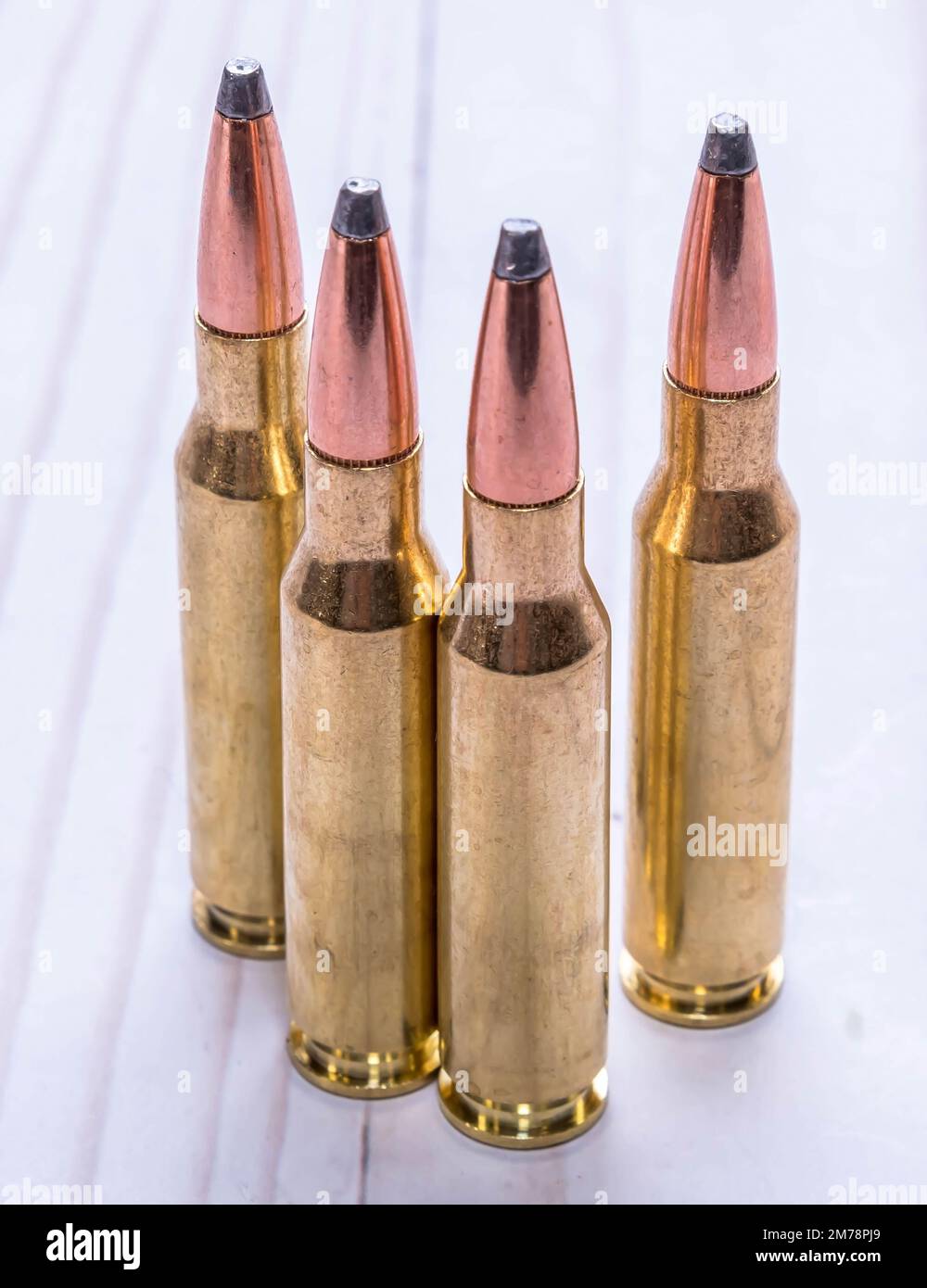 Quattro proiettili utilizzati per la caccia, due di calibro 30,06 e due di calibro 7mm-08 insieme su uno sfondo di legno bianco Foto Stock
