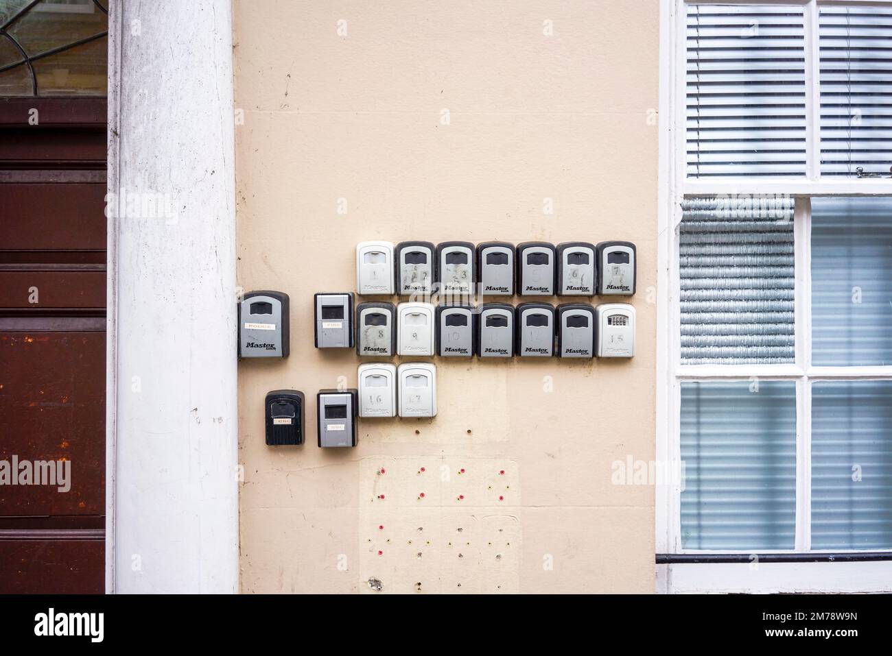 Piccole casseforti con chiavi che contengono le chiavi di un edificio fissato con serrature a combinazione attaccate a una parete Foto Stock