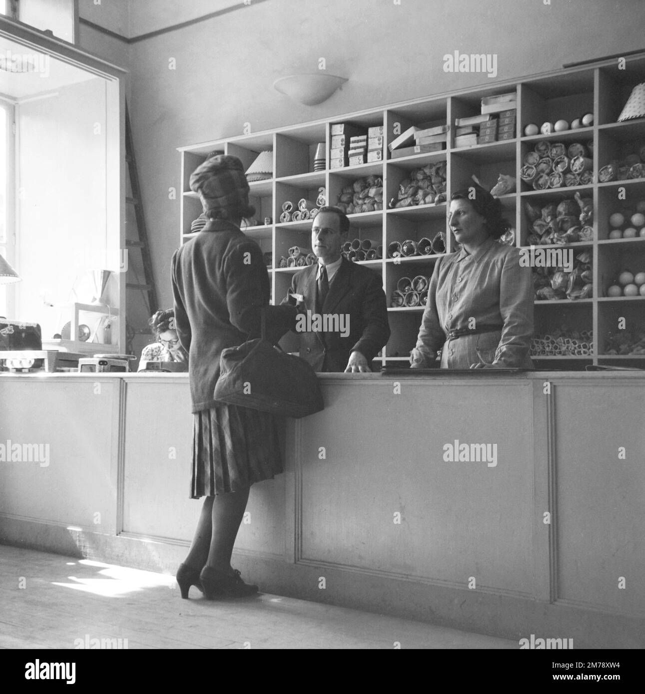 1940s Female o Donna Shopper, Negozio Assistenti o lavoratori in radio Canebiere elettronica e radio Shop interni, Marsiglia 1945. Fotografia vintage in bianco e nero o monocromatica. Foto Stock