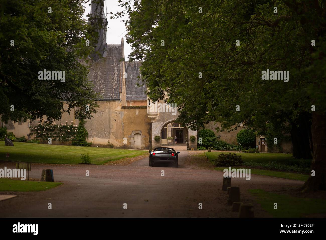 Una macchina sportiva nera, si trova vicino a un bellissimo castello storico in Europa Foto Stock