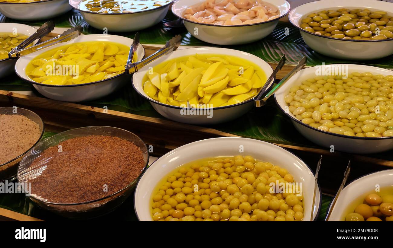 Stalla con grandi ciotole piene di fettine di mango sottaceto e altri frutti. Uno spuntino popolare in molti paesi del sud-est asiatico. Foto Stock