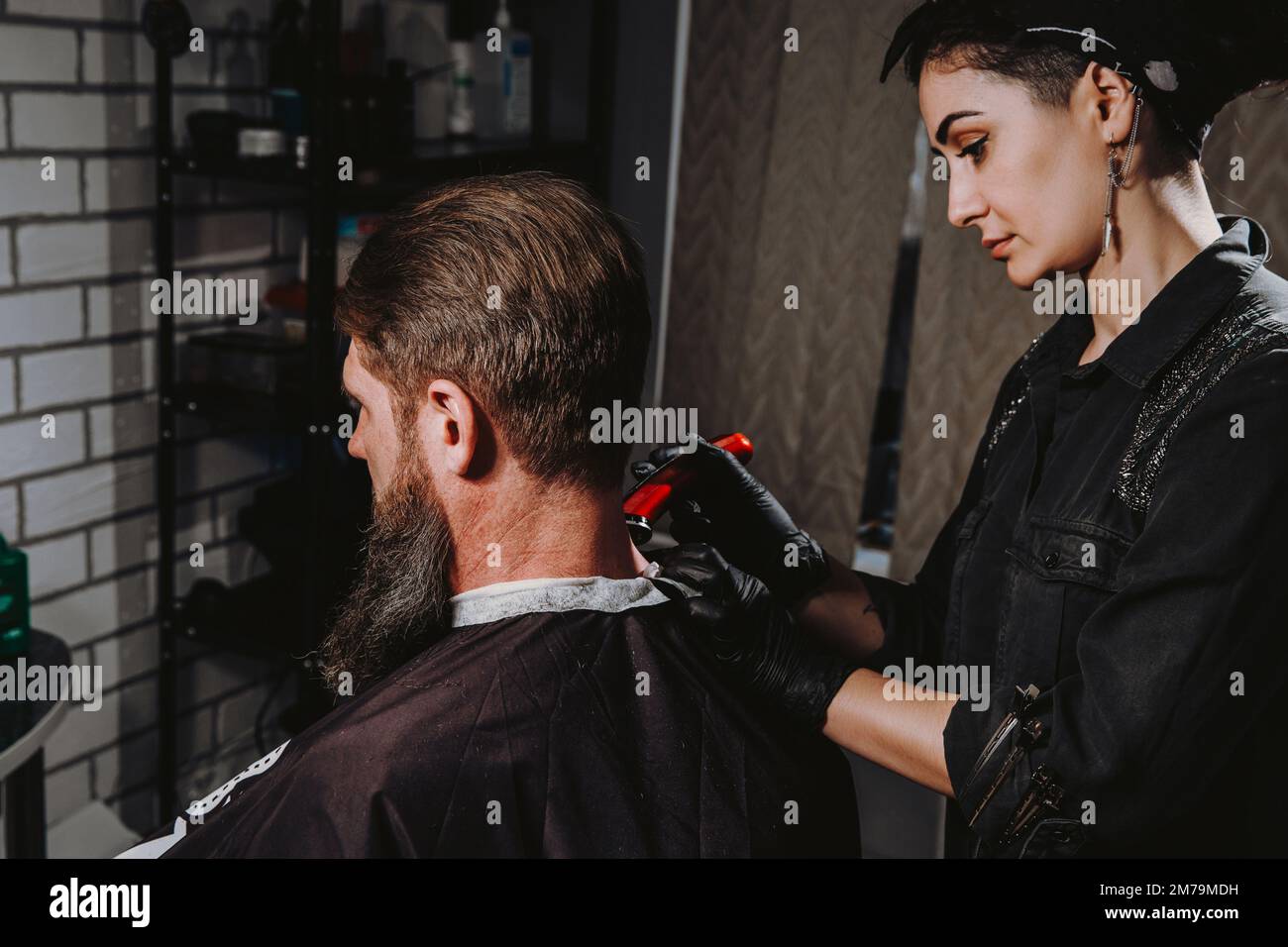 Primo piano top view immagine di uomo bearded ottenere capelli taglio da parrucchiere con vecchio stile rasoio pericoloso al barbiere mentre si siede in sedia. Concetto di industria di bellezza. Foto Stock