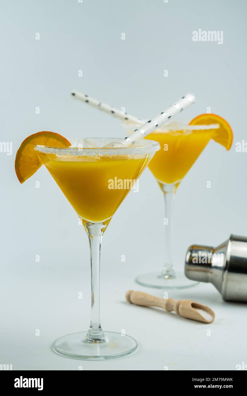Cocktail all'arancia naturale appena spremuto, in un bicchiere con uno shaker sul fondo Foto Stock