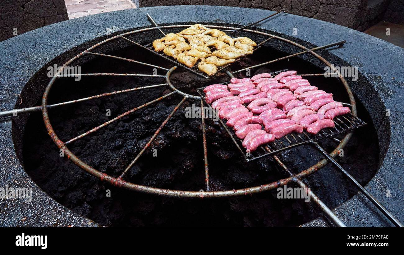 Barbecue sul buco della terra, cosce di pollo, salsicce, barbecue con calore della terra, centro visitatori, Parco Nazionale Timanfaya, montagne fuoco, vulcanico Foto Stock