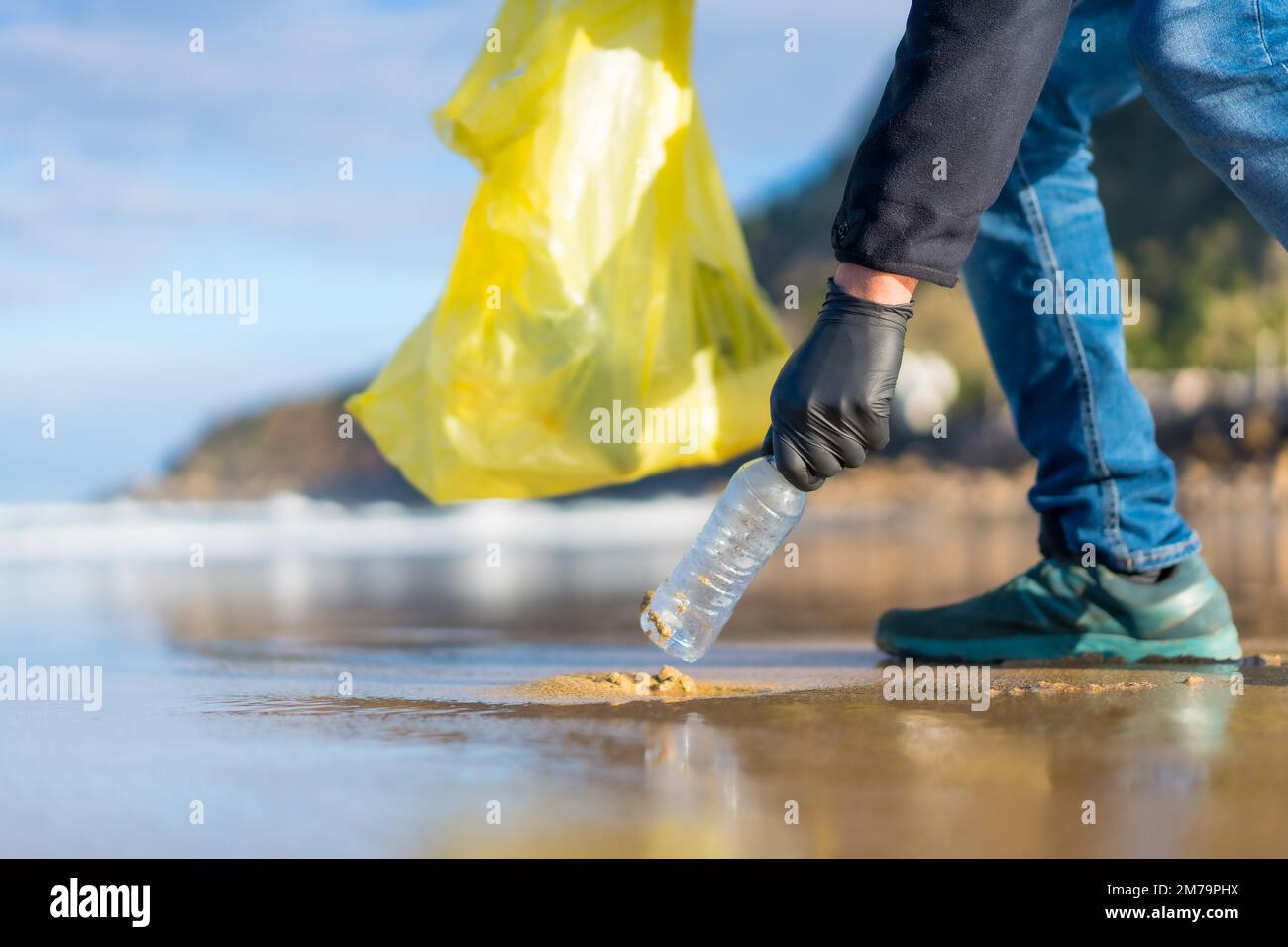Persona irriconoscibile che raccoglie rifiuti o plastica sulla spiaggia. concetto di ecologia Foto Stock