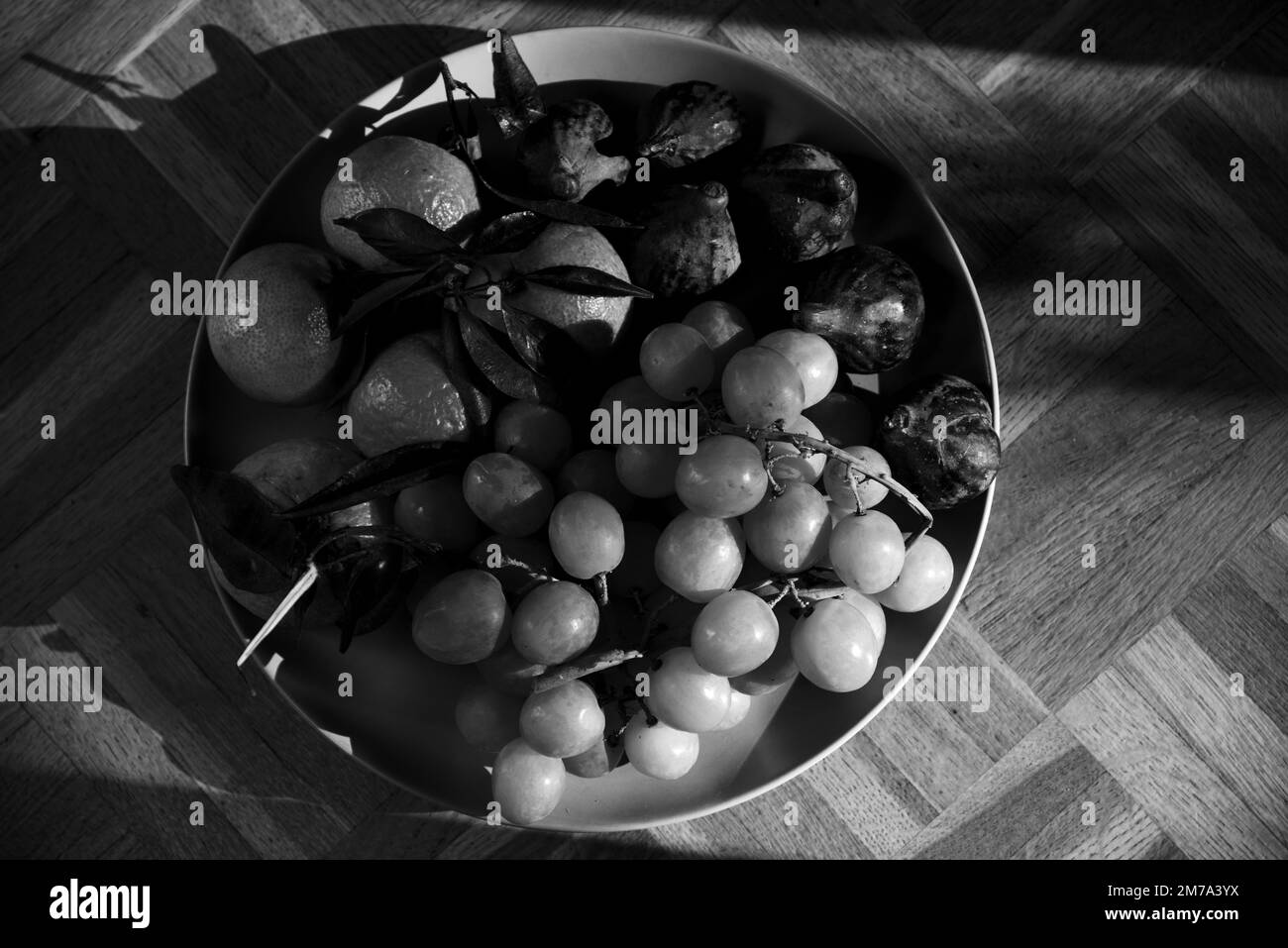 Frutti biologici diversi dal mercato contadino locale su piatto su vecchia superficie rustica di legno. Frutta di stagione sfondo. Fotografia in bianco e nero Foto Stock