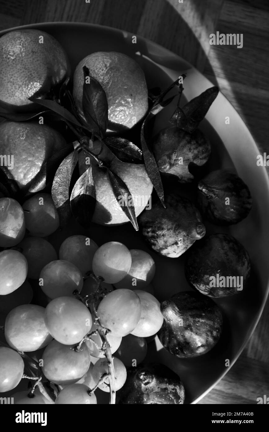 Frutti biologici diversi dal mercato contadino locale su piatto su vecchia superficie rustica di legno. Frutta di stagione sfondo. Fotografia in bianco e nero Foto Stock