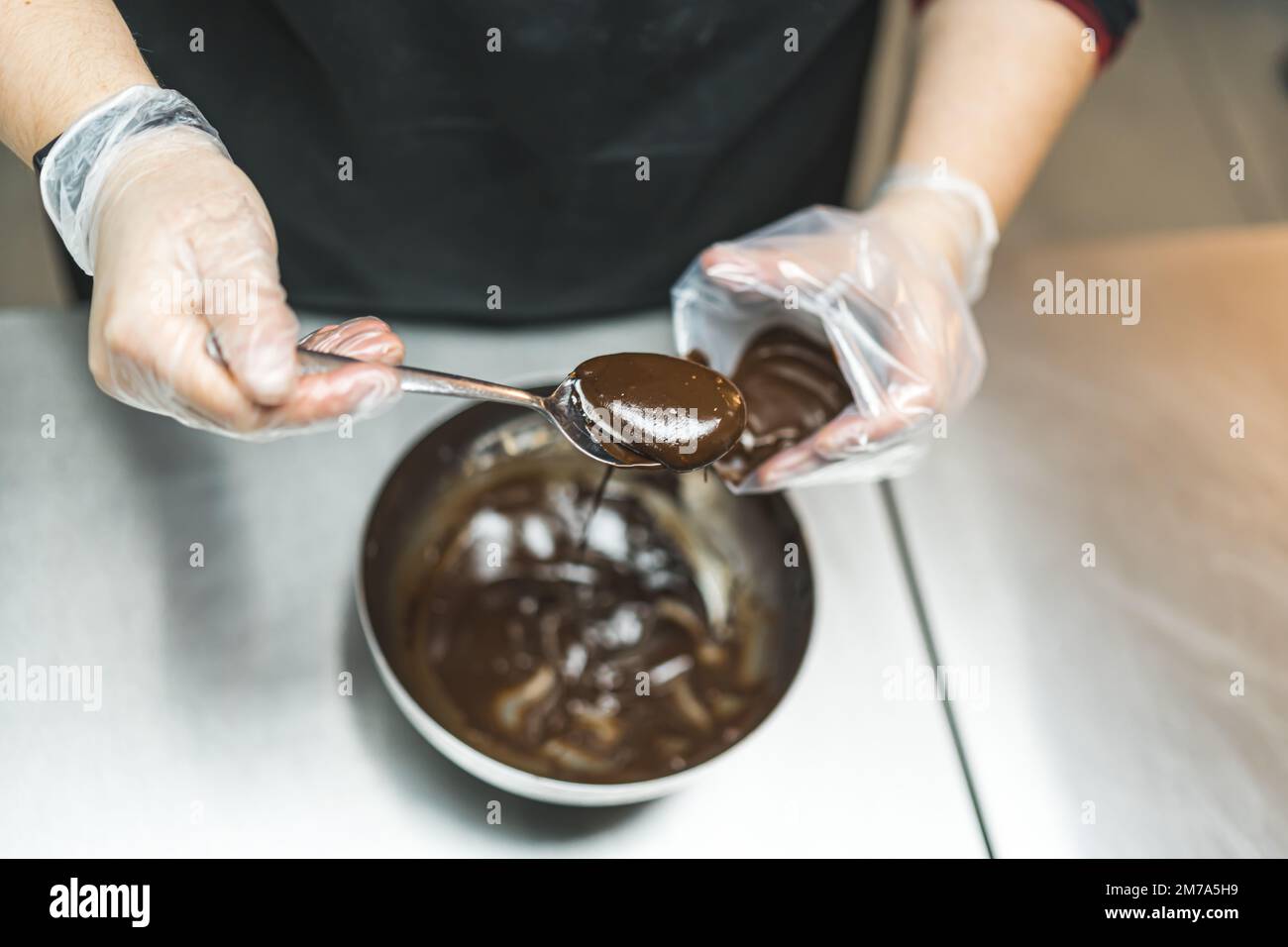 Vista dall'alto un esperto che mette la glassa di cioccolato in un sacchetto di pasta forma una ciotola di metallo con un cucchiaio. Foto di alta qualità Foto Stock