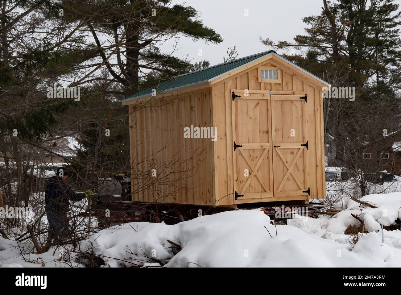 Un deposito prefabbricato in legno che viene consegnato e messo in atto dopo una tempesta di neve pesante Foto Stock