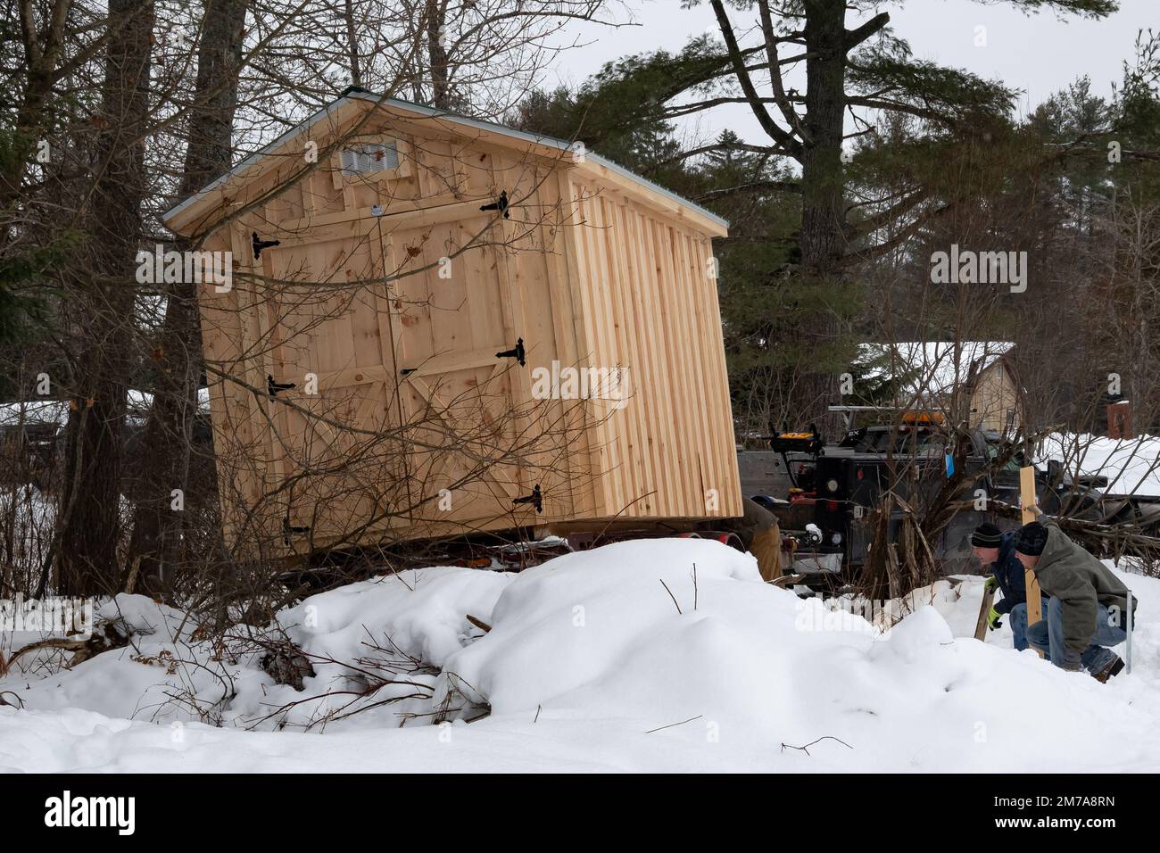 Un deposito prefabbricato in legno che viene consegnato e messo in atto dopo una tempesta di neve pesante Foto Stock