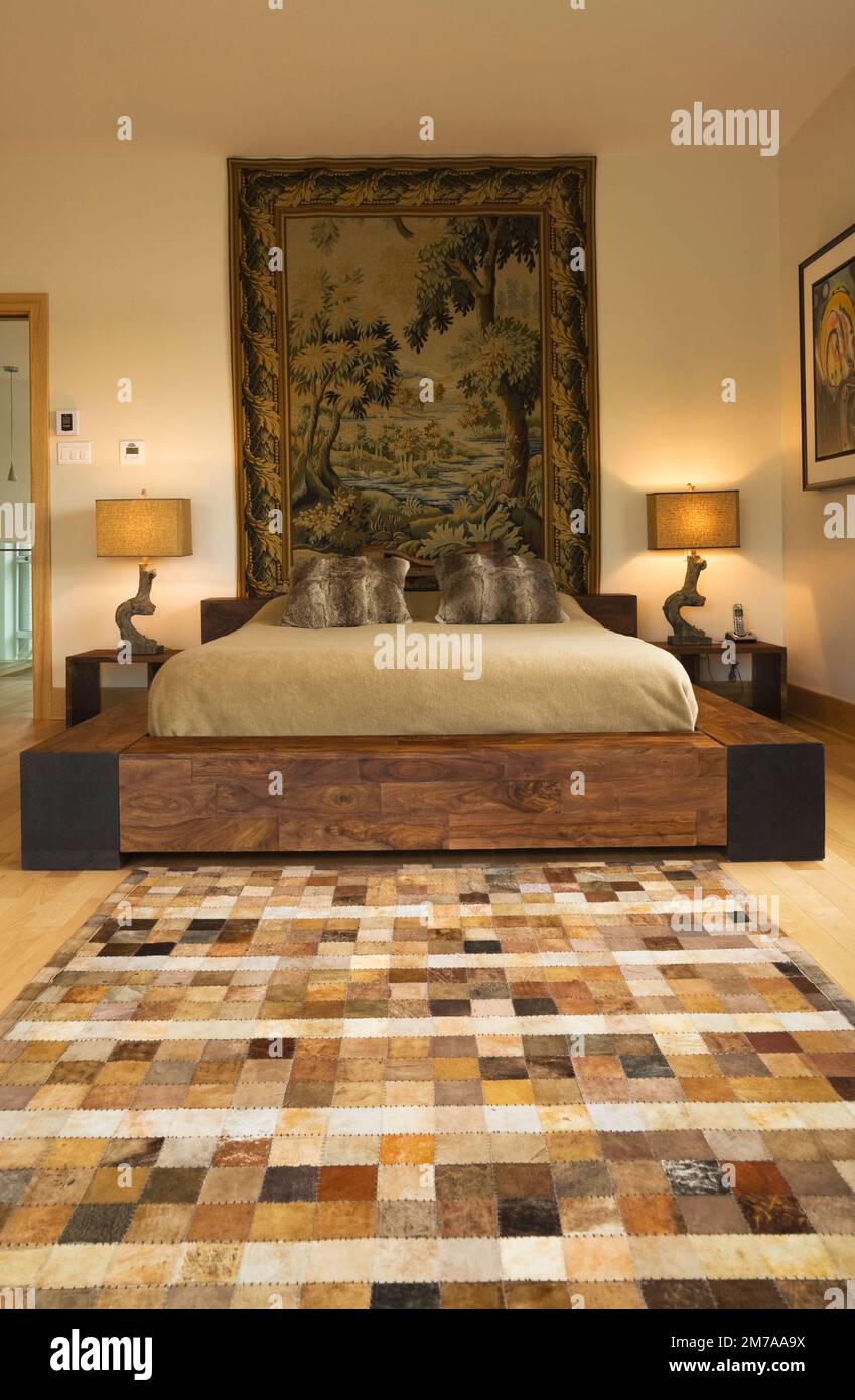 Letto king size con struttura in legno e arazzi panoramici a parete nella camera da letto principale al piano superiore, all'interno di una casa moderna in stile cubista. Foto Stock