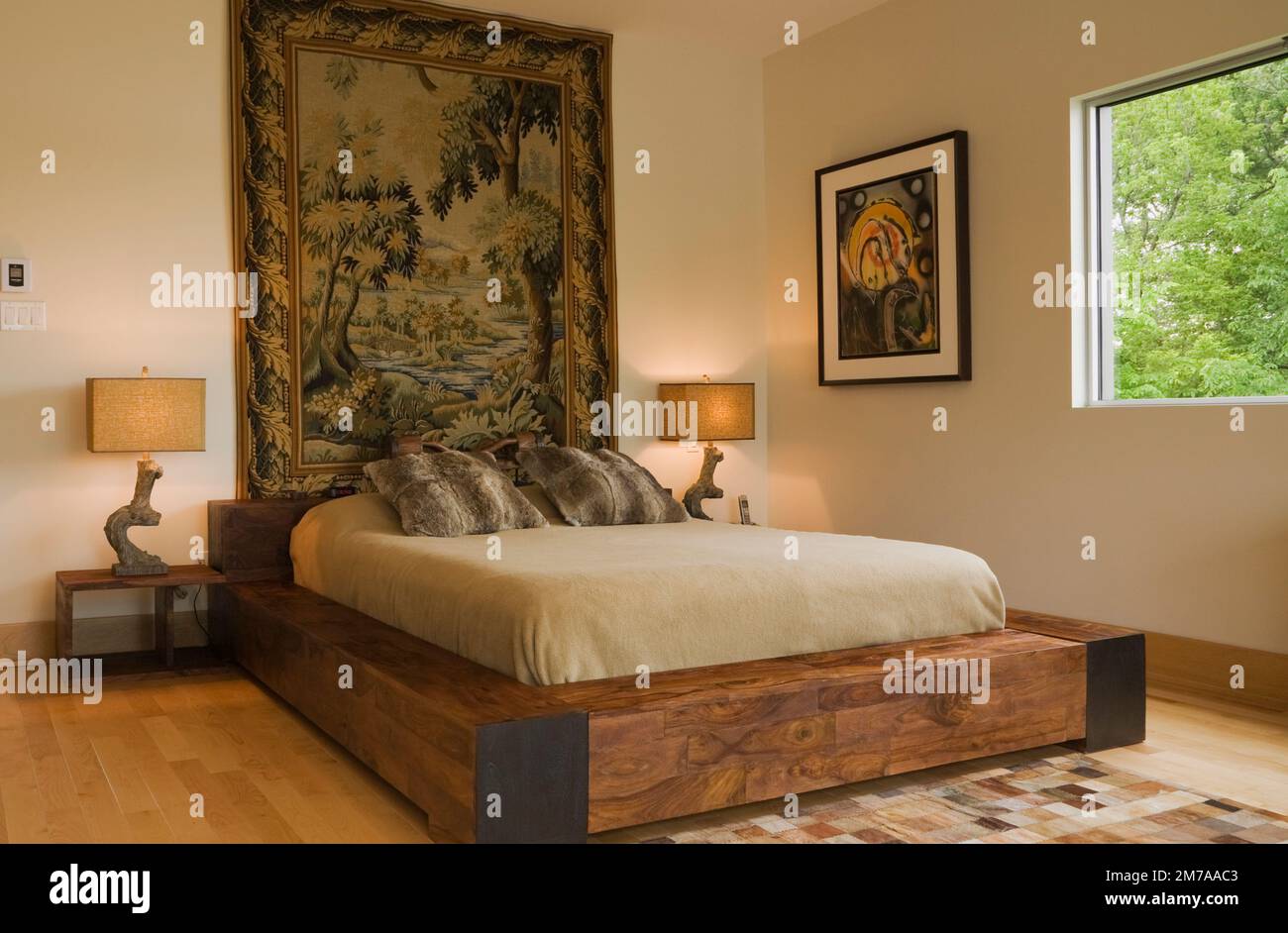 Letto king size con struttura in legno e arazzi panoramici a parete nella camera da letto principale al piano superiore, all'interno di una casa moderna in stile cubista. Foto Stock