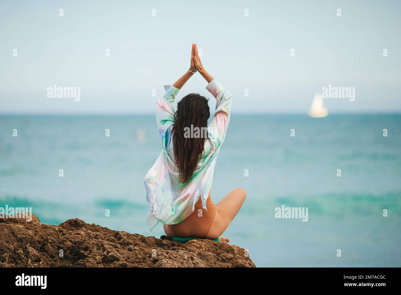 Giovane donna con yoga in spiaggia Foto Stock
