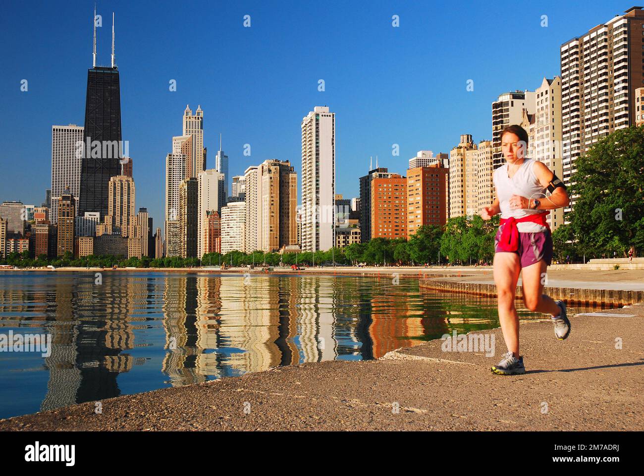 Una giovane donna scherza lungo il lungolago con lo skyline di Chicago che sorge dietro di lei Foto Stock