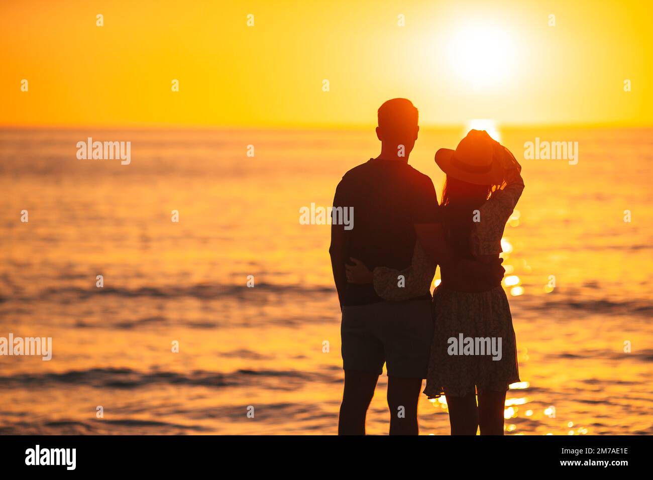 Coppia romantica sulla spiaggia al tramonto colorato su sfondo Foto Stock