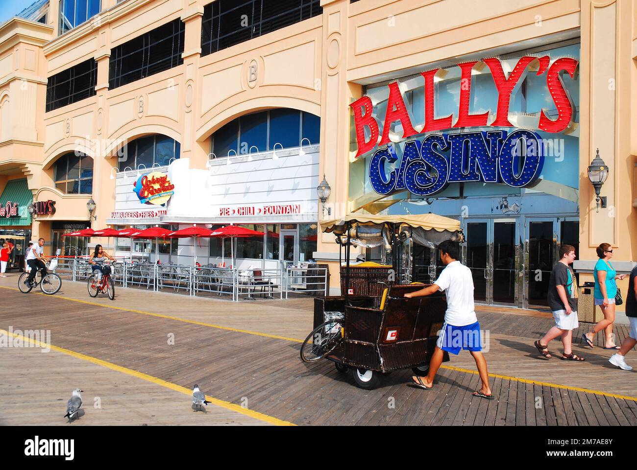 Un uomo adulto spinge il suo pedicab con un passeggero all'interno, di fronte ai casinò sul lungomare di Atlantic City, New Jersey, in una giornata di sole estate Foto Stock