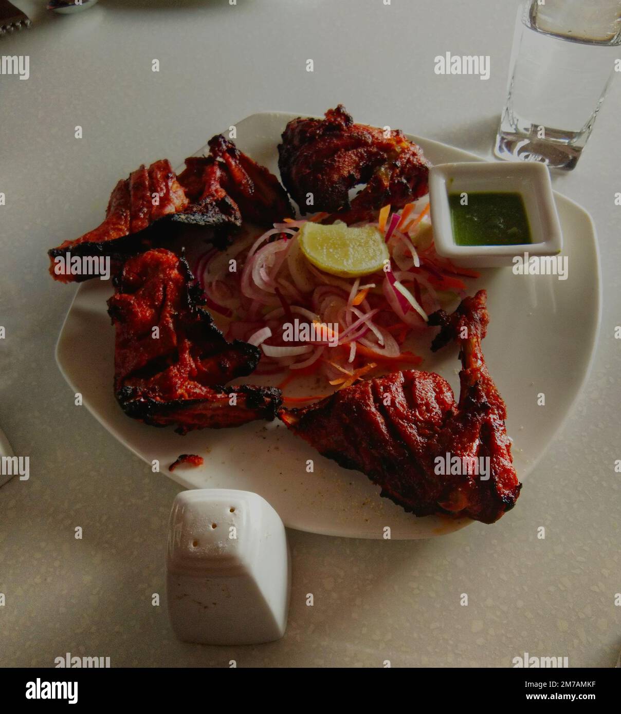 piatto di pollo tandoor con limone, insalata, sale, chutney verde in modo indiano. Foto Stock