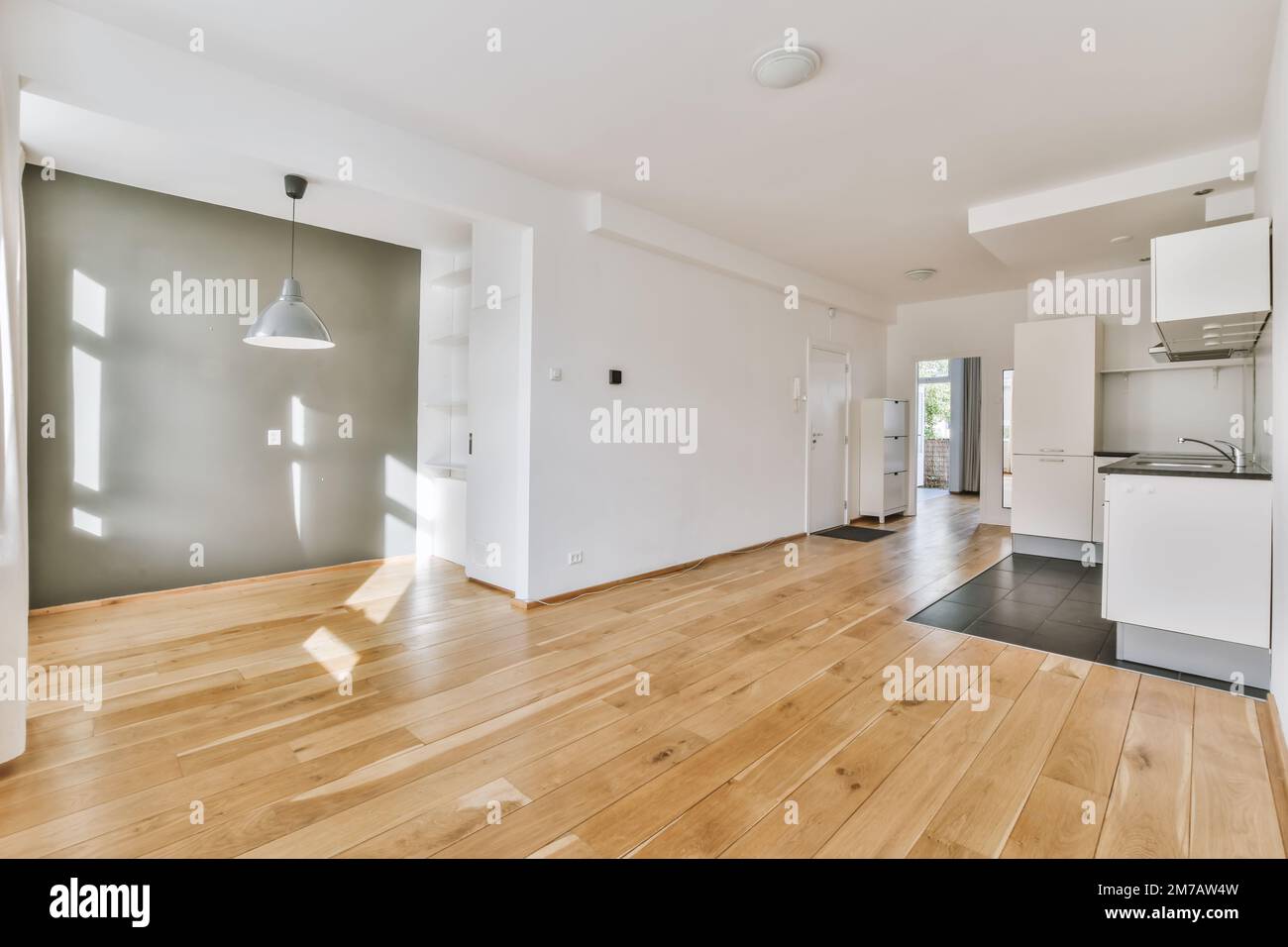 un soggiorno vuoto con pavimento in legno e elettrodomestici bianchi sulla parete della camera è di colore molto chiaro Foto Stock