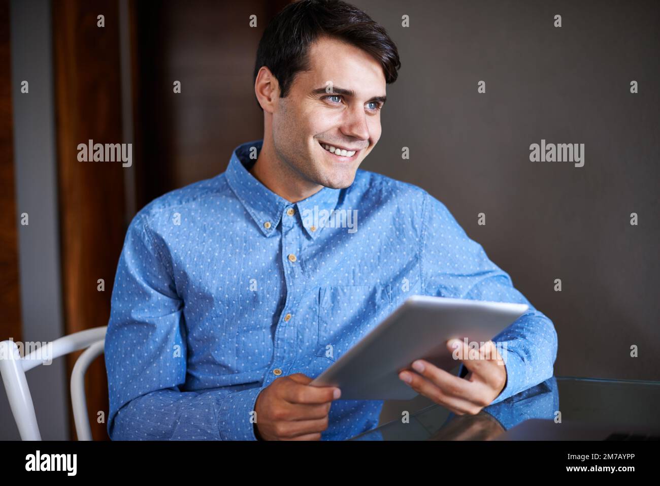 Pensare ai piani per estendere la sua base di clienti. un giovane uomo d'affari sorridente seduto con il suo tablet digitale. Foto Stock