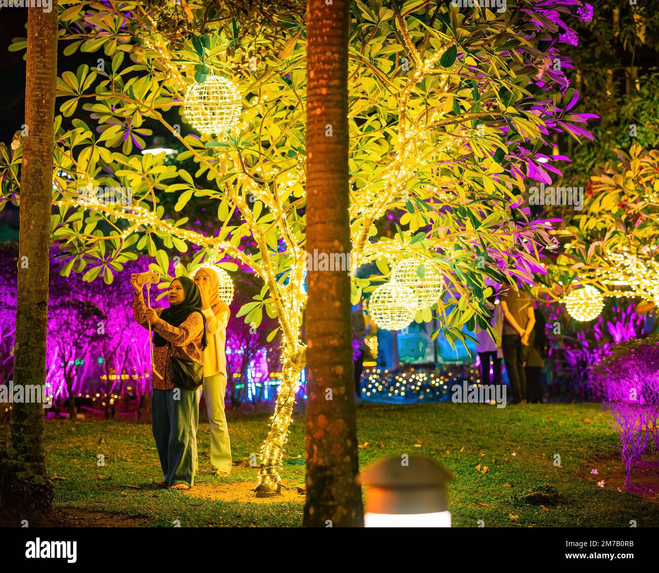Putrajaya, Malesia - 18 luglio 2022 Poeple scattare foto con luci a LED sugli alberi nel giardino. Festa delle fata al neon. Foto Stock