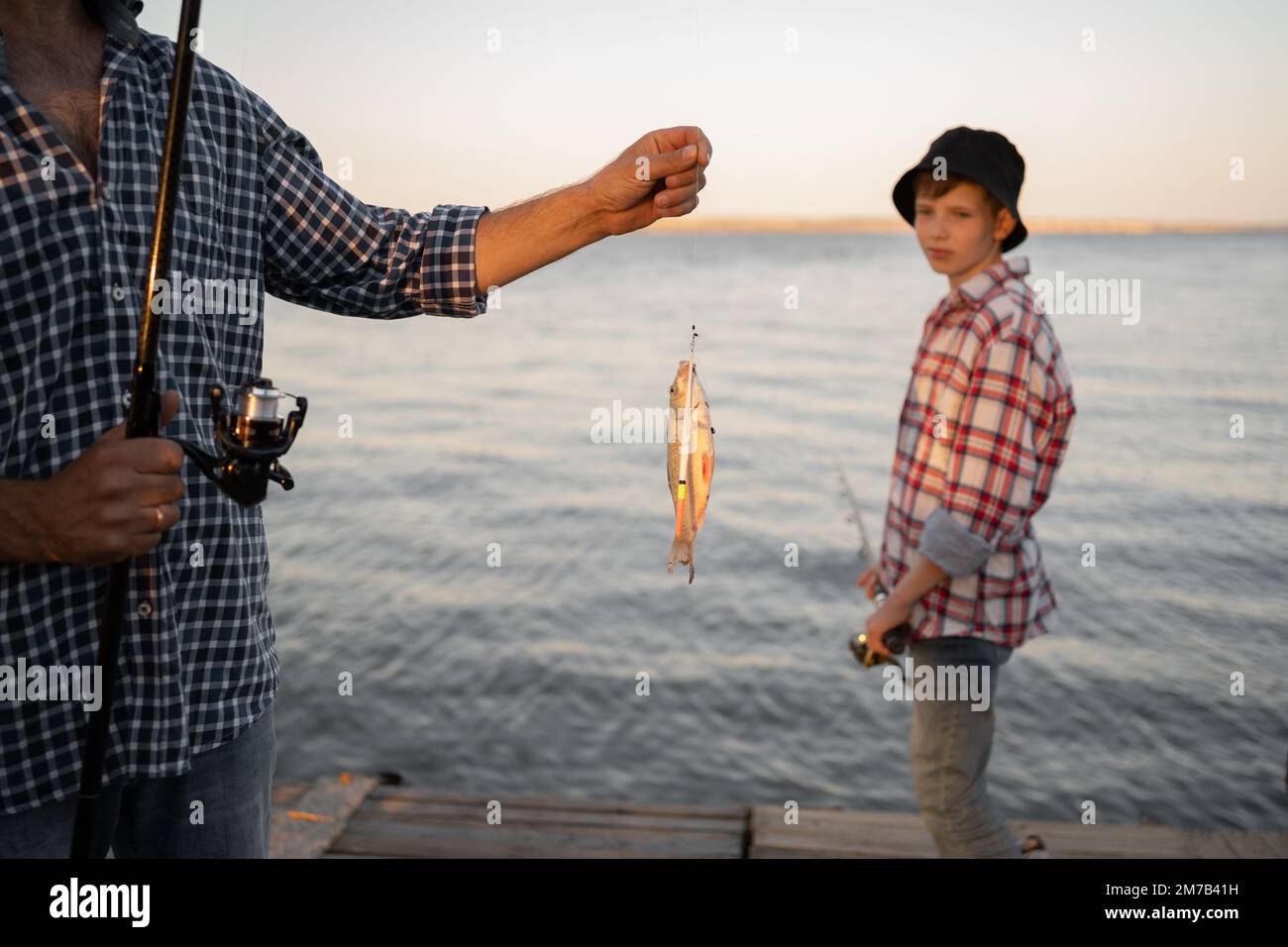 L'uomo catturò un figlio di un ragazzo di pesce sullo sfondo. Foto Stock