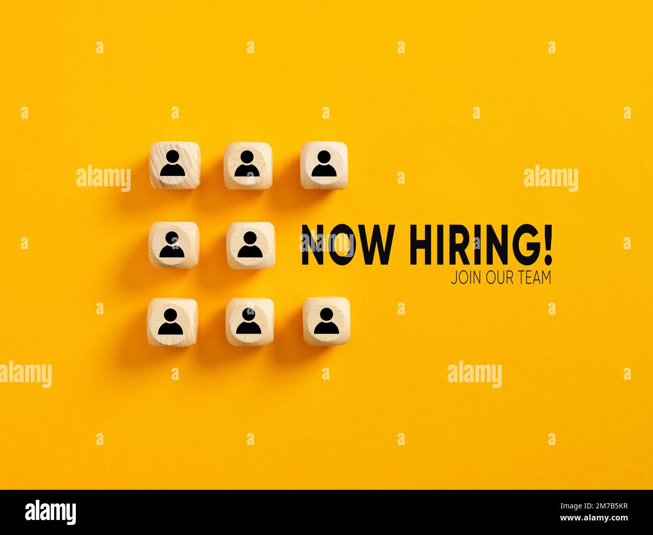 I simboli dei dipendenti su blocchi di legno con il messaggio ora assumere unirsi al nostro team. Occupazione, assunzione e concetto di business. Foto Stock