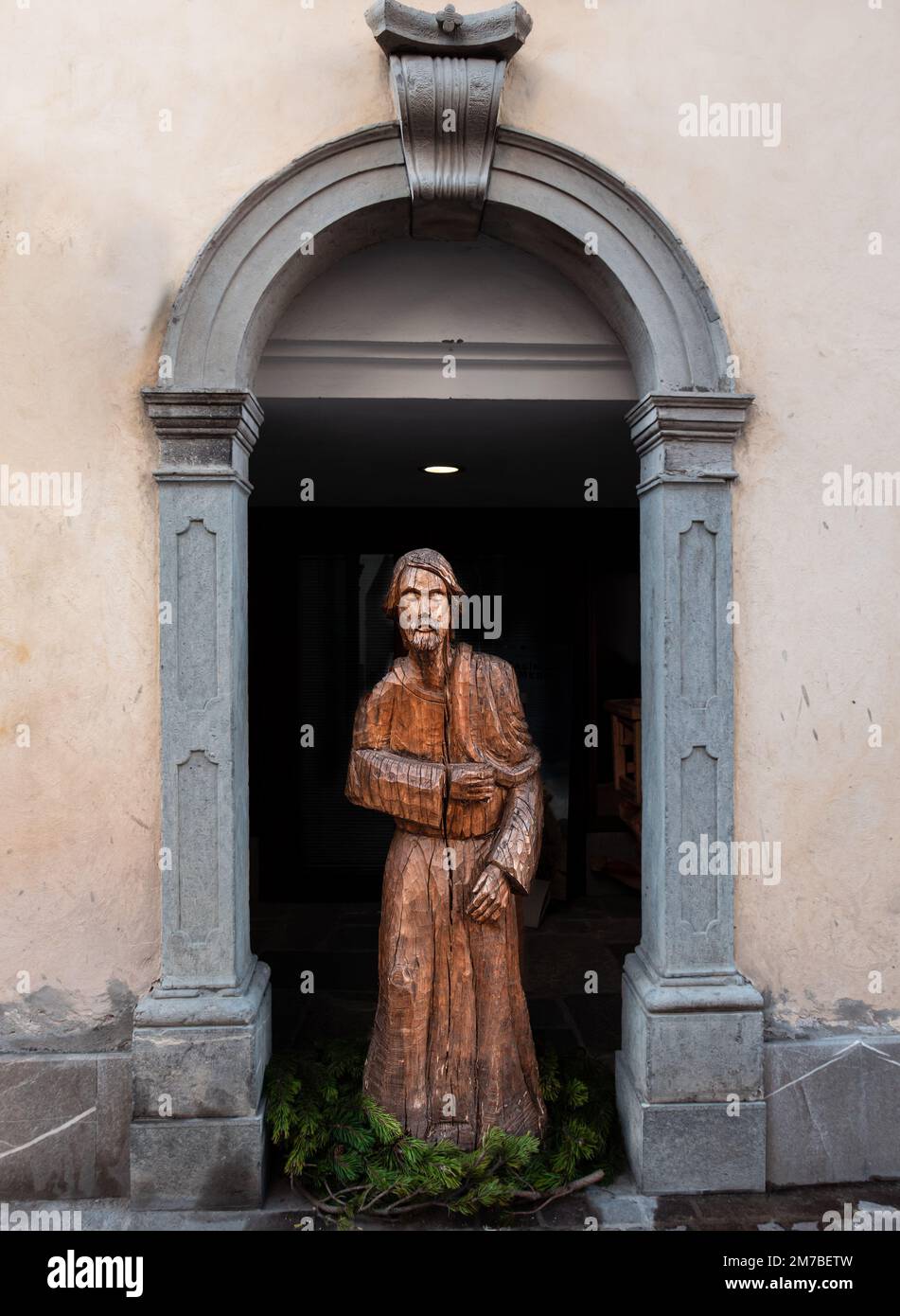 Sutrio, Italia - 29 dicembre 2022: Scultura lignea a grandezza naturale di un uomo sotto una porta ad arco nel villaggio di Sutrio Foto Stock