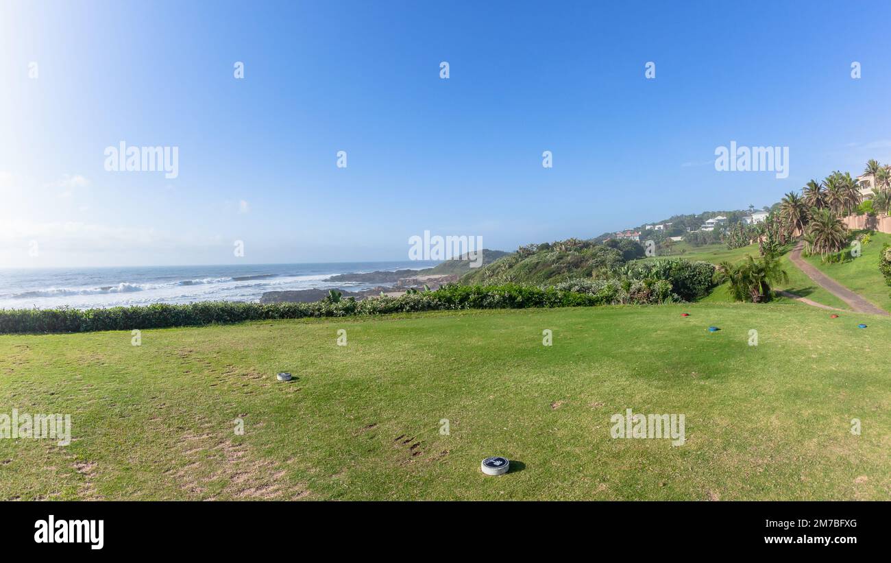 Campo da golf disposizione panoramica della spiaggia costiera buca oceano Tee box lontano putting verde circondato da vegetazione estate blu cielo paesaggio. Foto Stock