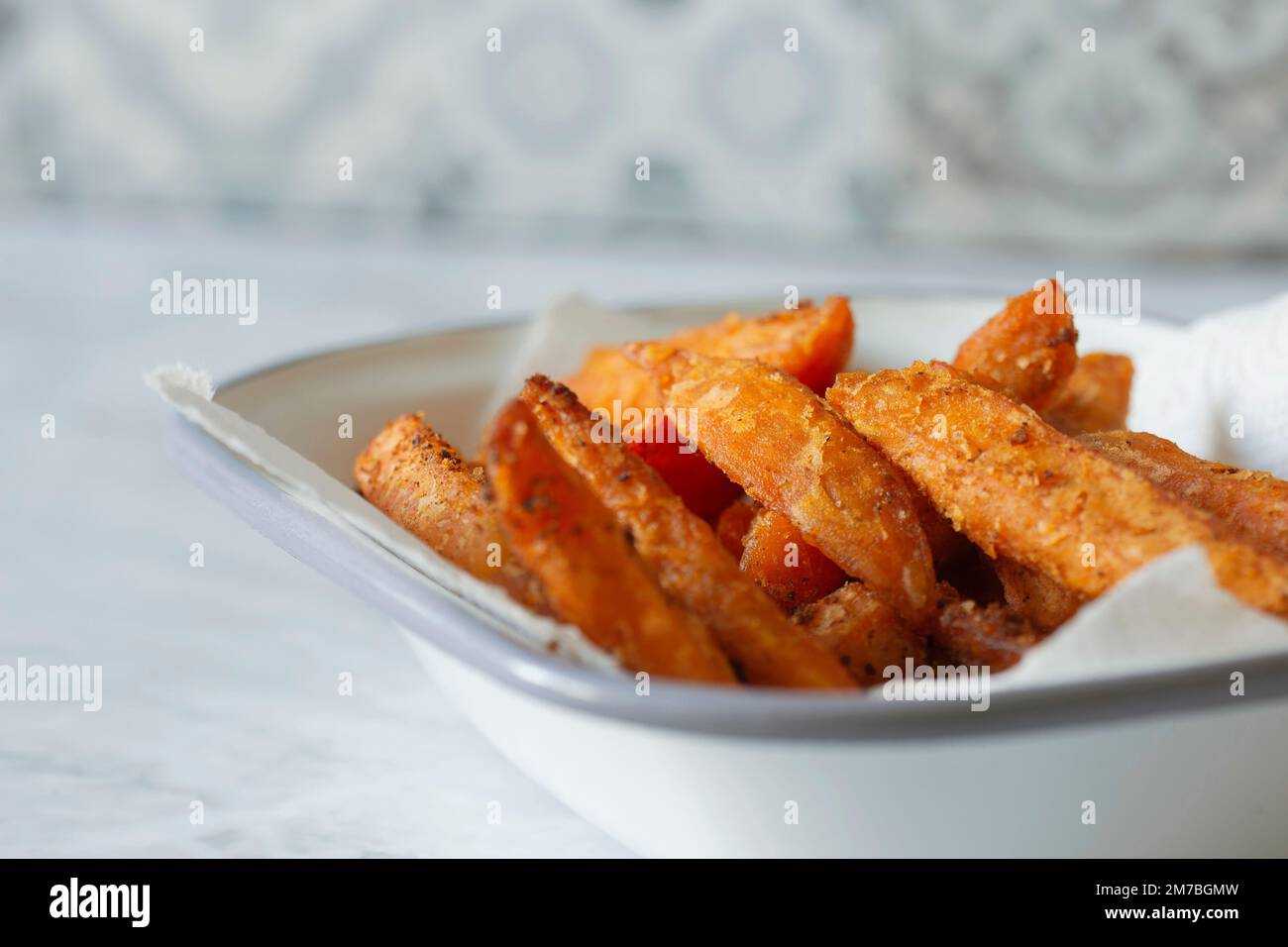 Patata dolce patatine fritte in una ciotola di smalto bianco. Su sfondo marmoreo Foto Stock