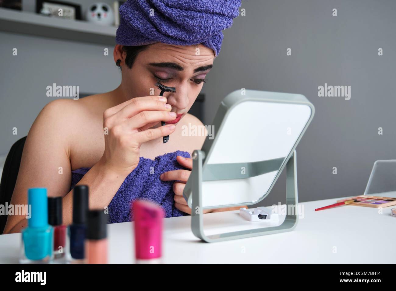 Giovane trascinare regina attaccando false ciglia. Foto Stock