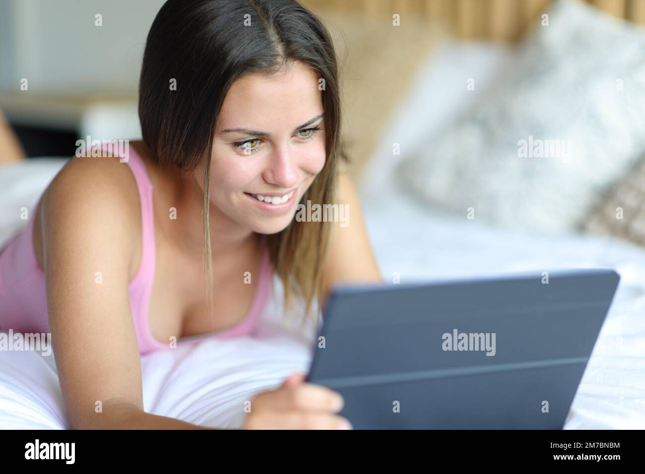 Felice adolescente utilizzando tablet sdraiato sul letto Foto Stock