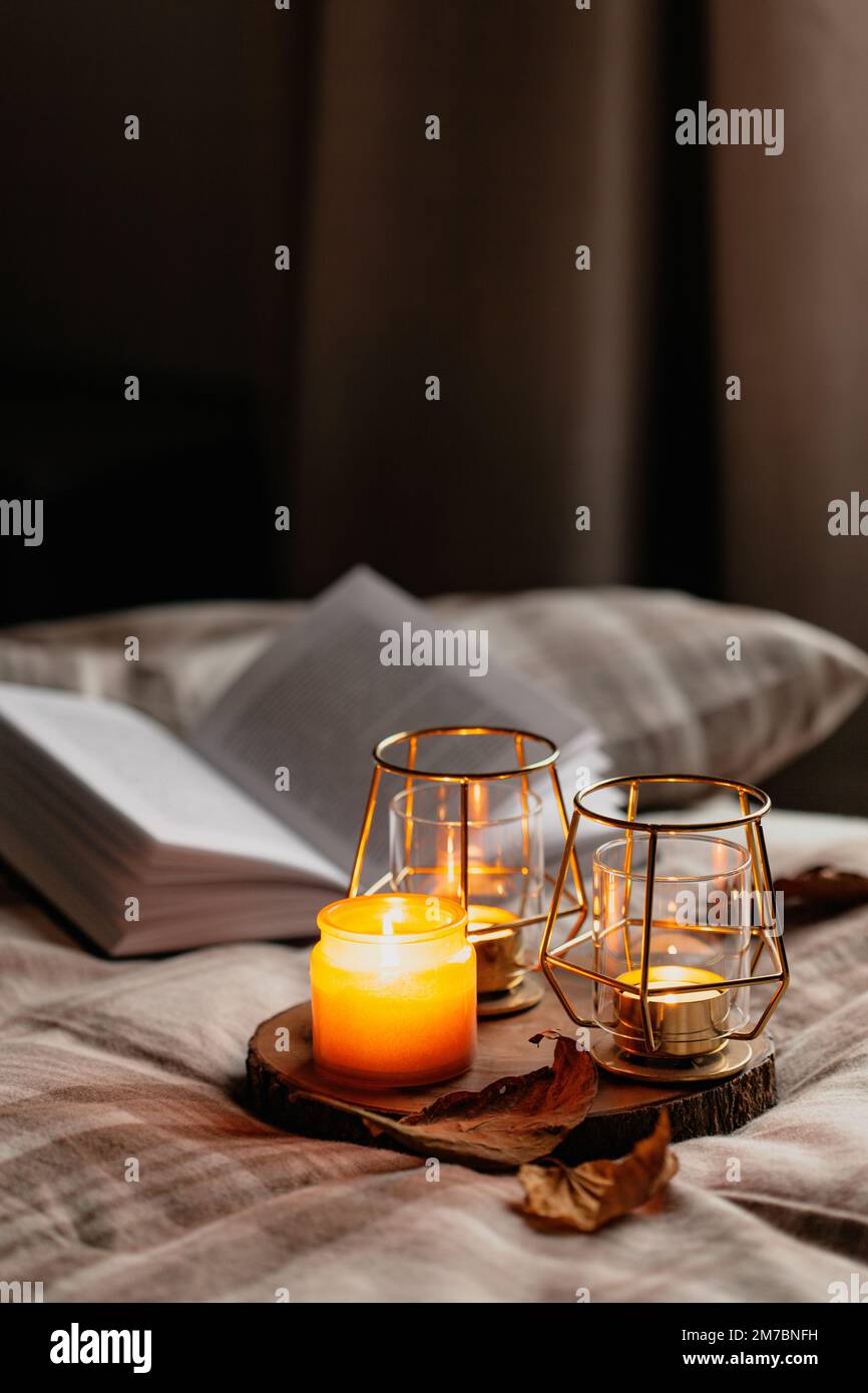 calda camera accogliente inverno o autunno concetto, candele su vassoio e un libro Foto Stock