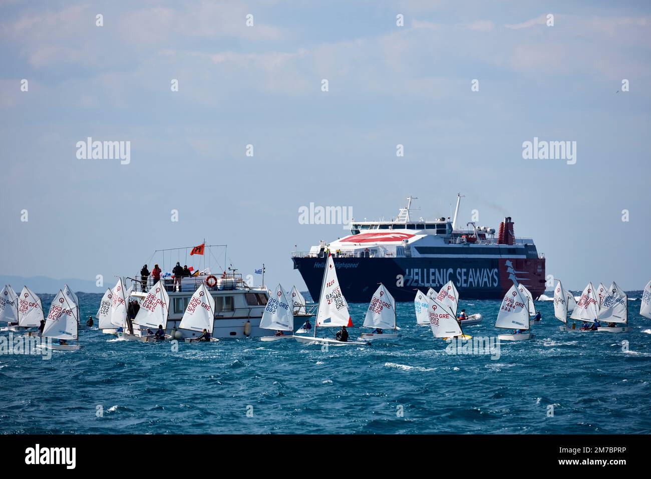 Piccole barche a vela in fila all'allenamento in mare aperto e grande nave traghetto sul retro Foto Stock