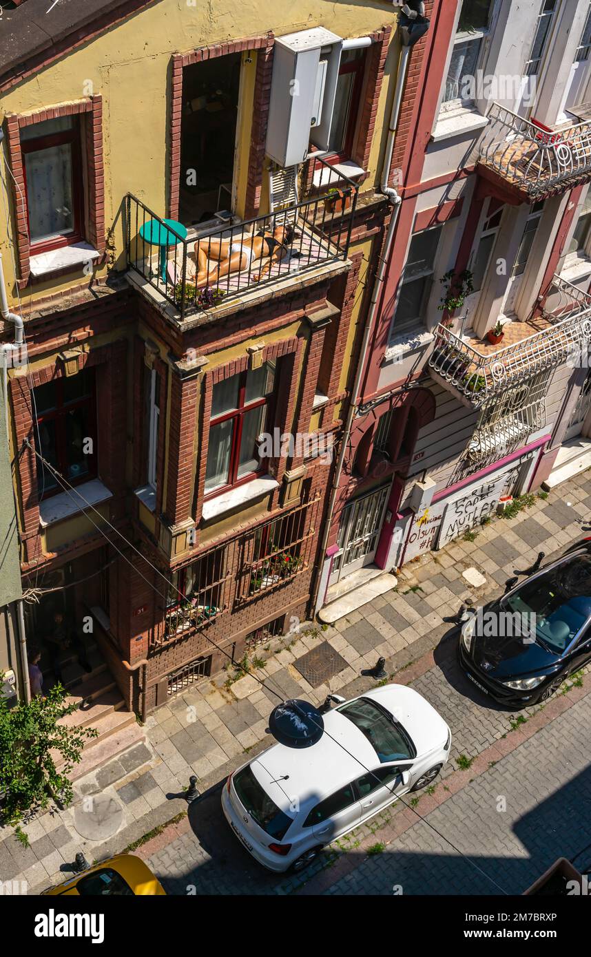 Vista dall'alto del quartiere storico di Rasimpaşa a Kadikoy, Istanbul, Turchia. Una donna che prende il sole sul balcone durante le calde giornate estive. Foto Stock