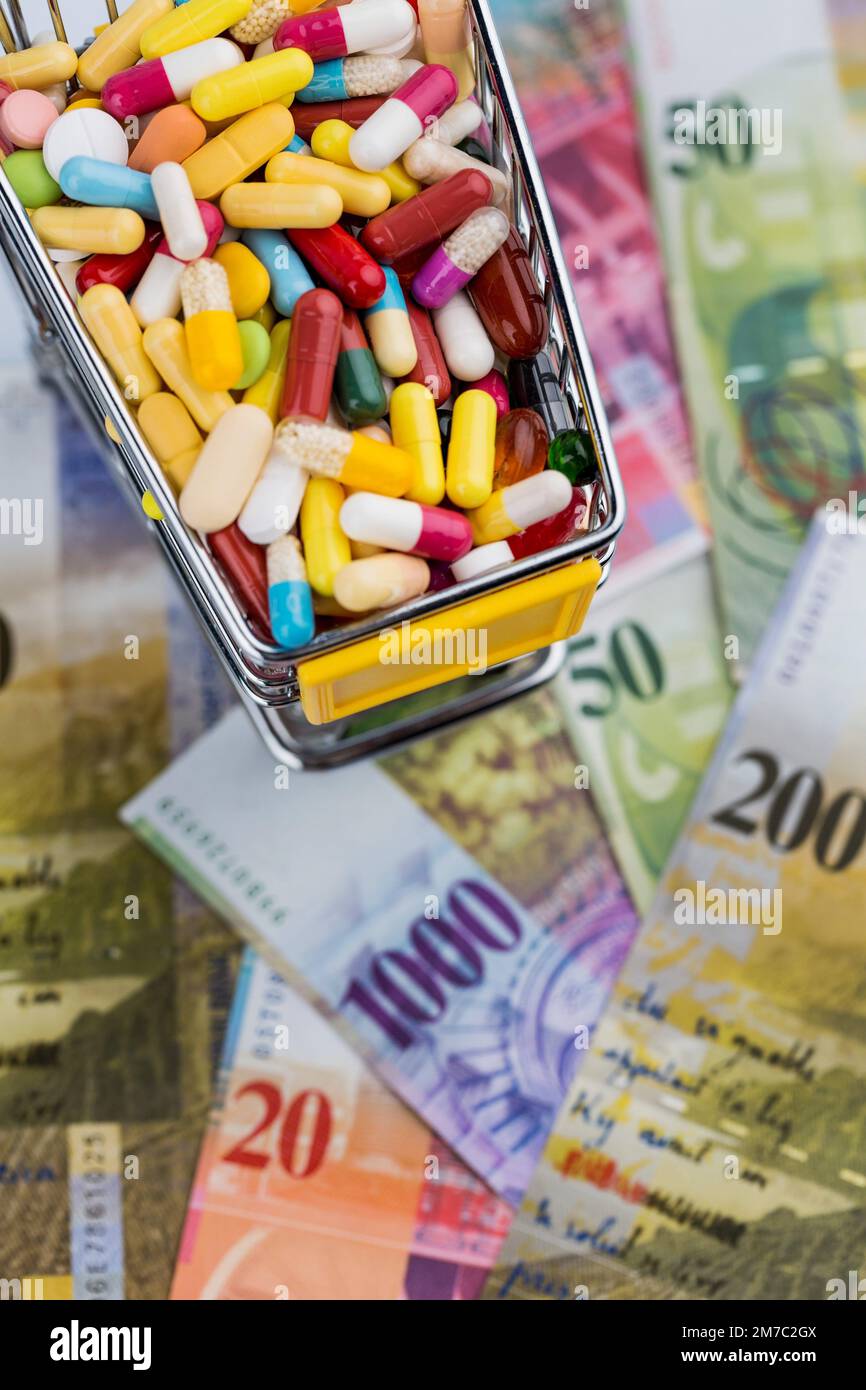 Pillole colorate in un carrello con franchi svizzeri, ritaglio Foto Stock