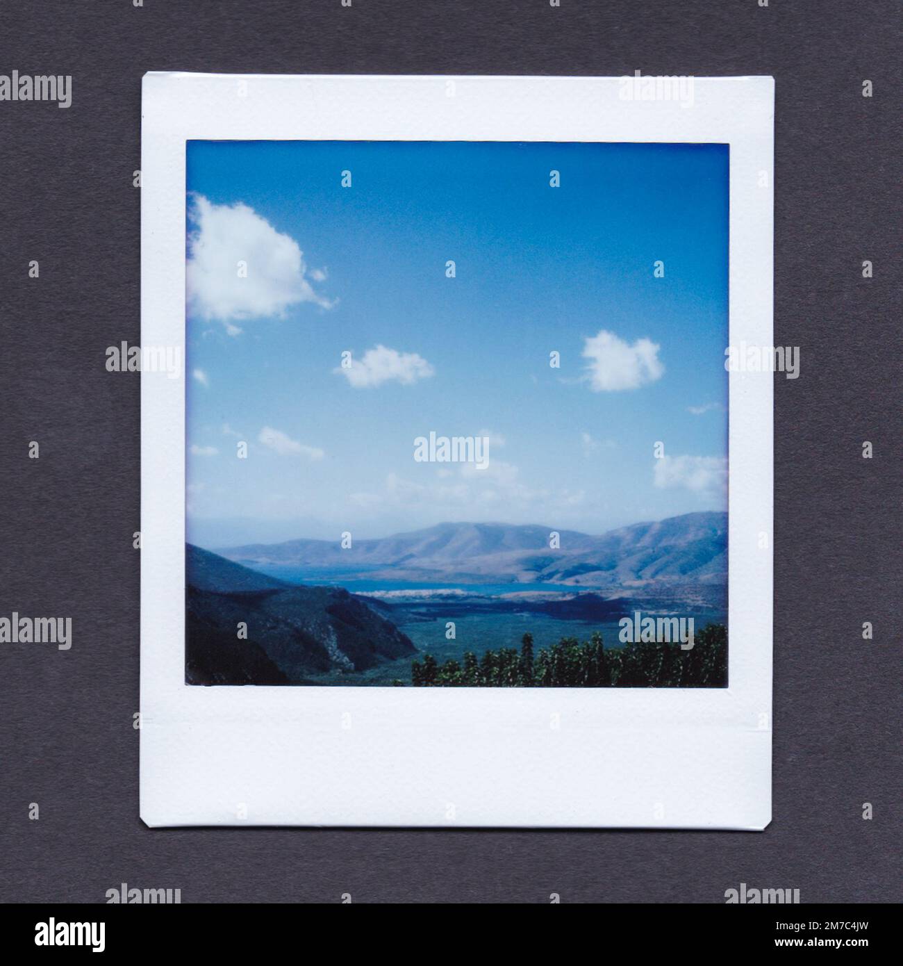 INSTAX Fotografia della vista attraverso la valle di Delfi, Grecia, mostrando montagne lontane dietro l'acqua, e cielo blu e nuvole nel cielo sopra. Foto Stock