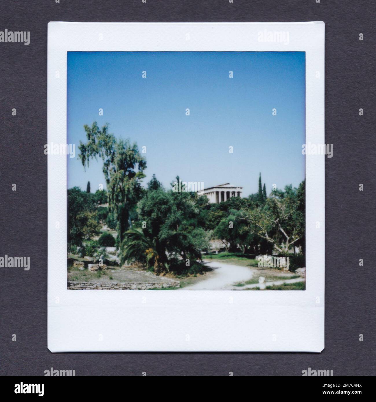 INSTAX Fotografia dell'antica Agorà di Atene, che mostra un tempio circondato da alberi e piante, un sentiero che porta verso di essa e cielo blu sopra. Foto Stock