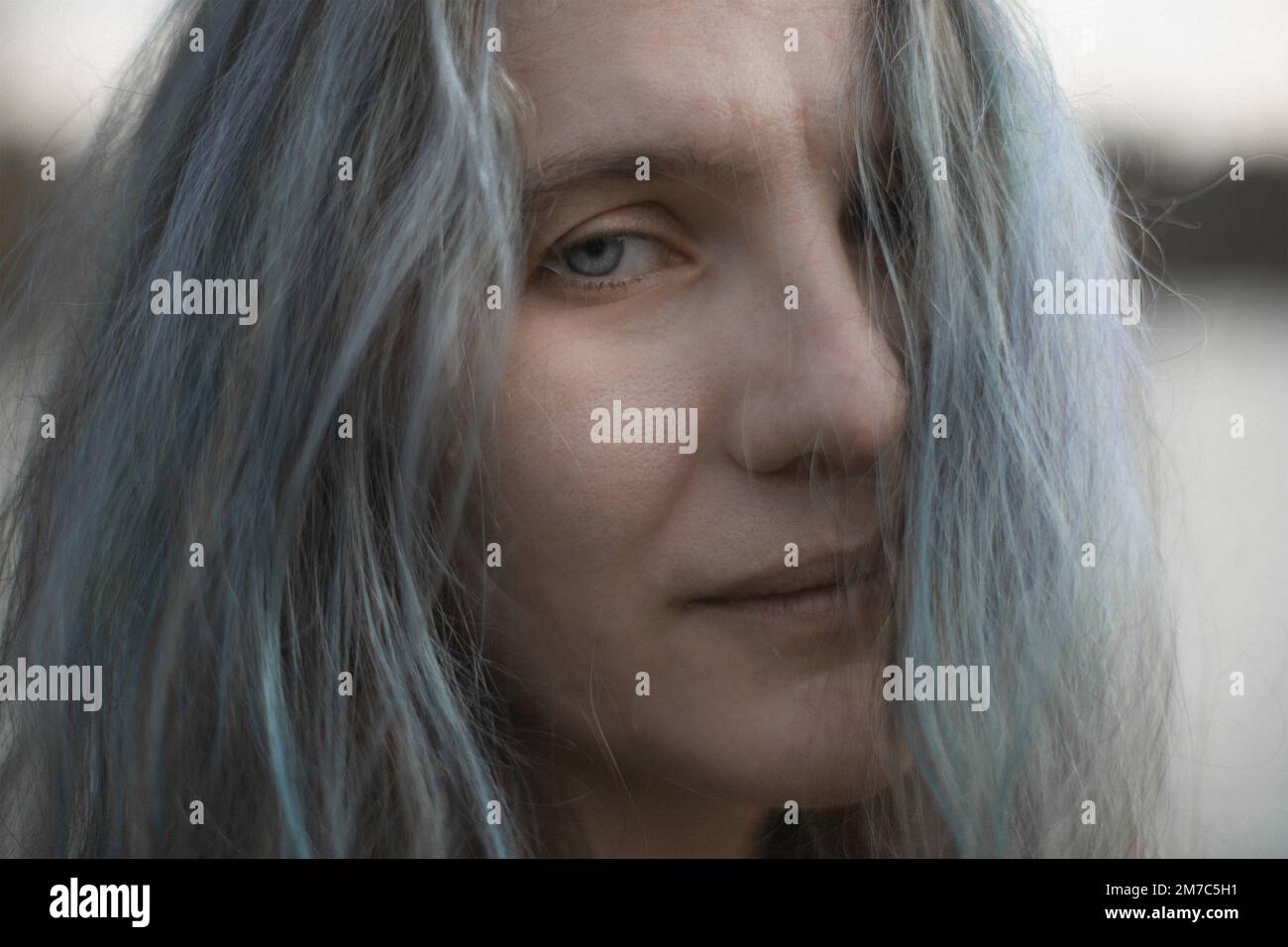 Primo piano donna dagli occhi blu con i capelli grigi guardando avanti con immagine ritratto sorriso Foto Stock