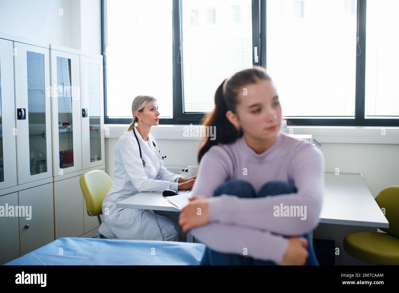 Ragazza adolescente infelice seduta nell'ufficio del medico. Foto Stock