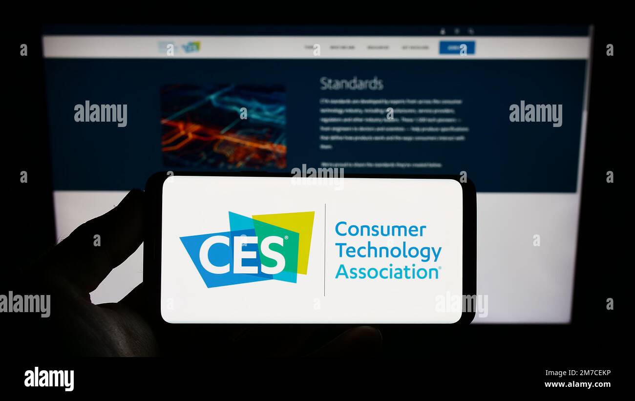 Persona che tiene lo smartphone con il logo della US Consumer Technology Association (CTA, CES) sullo schermo davanti al sito Web. Messa a fuoco sul display del telefono. Foto Stock