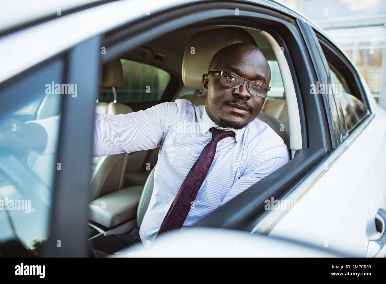 Ritratto di un bell'uomo d'affari afroamericano di successo alla guida della sua auto Foto Stock