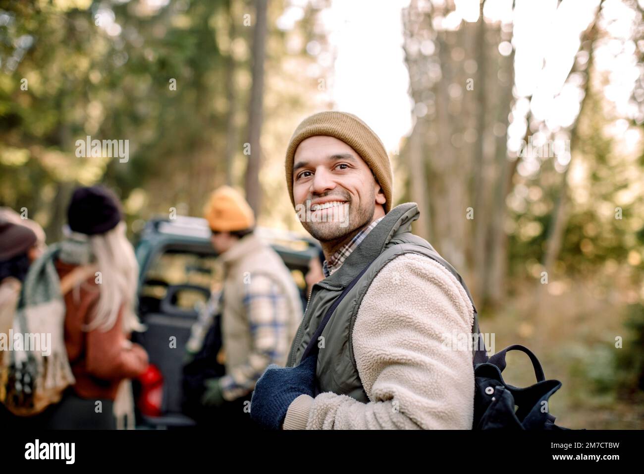 Uomo sorridente che indossa abiti caldi contemplando nella foresta Foto Stock