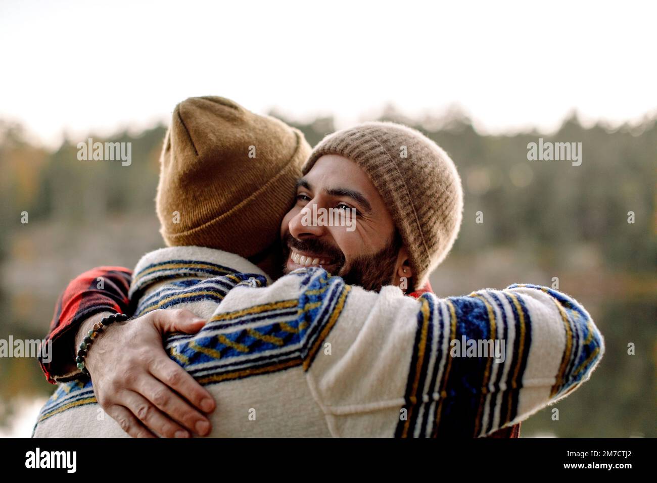 Amici maschi felici che si abbracciano indossando cappelli in maglia Foto Stock