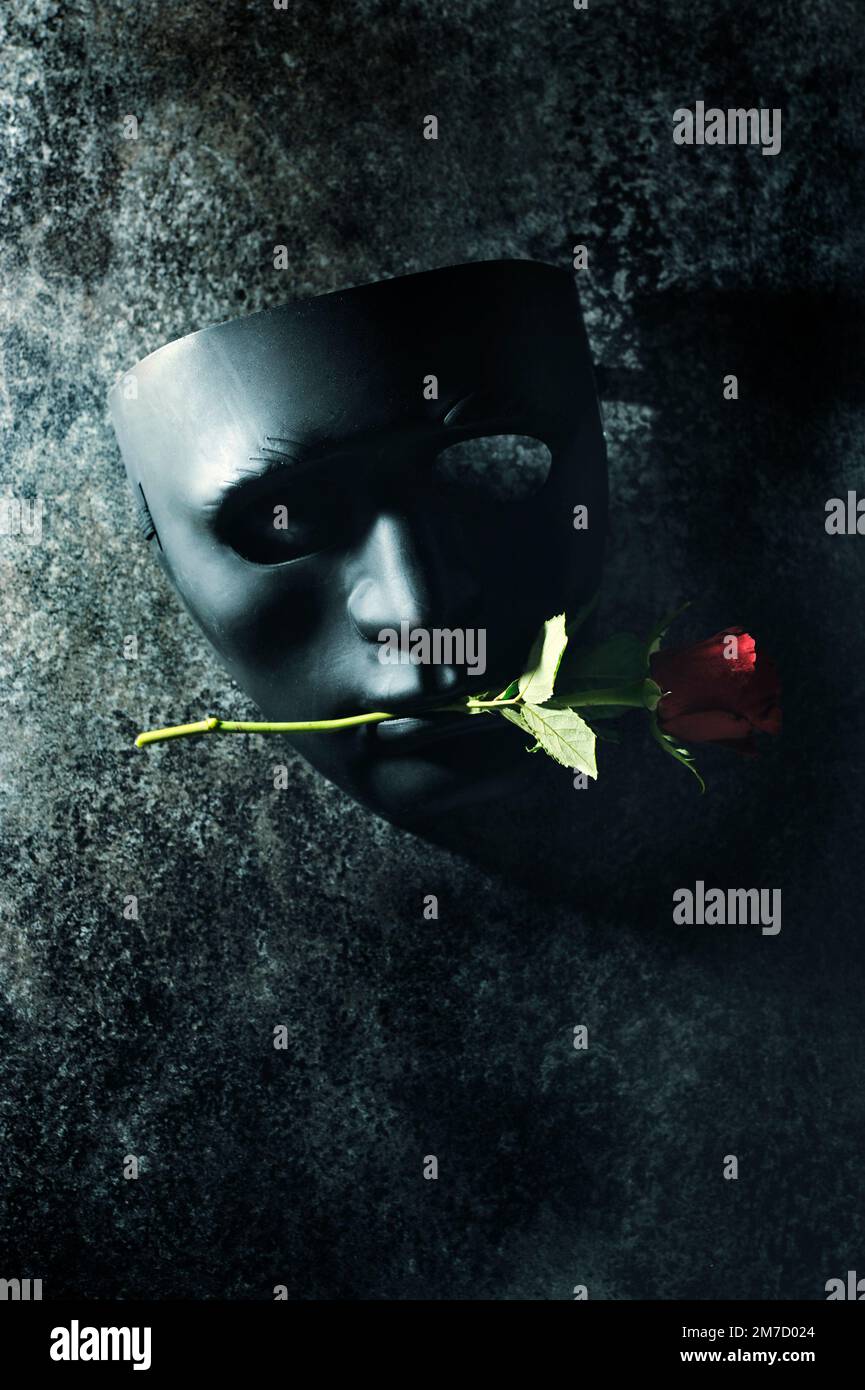 maschera nera con rosa rossa in bocca Foto Stock